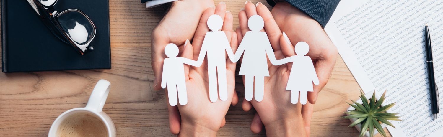 Hände halten Papierschnitte von Familienfiguren.
